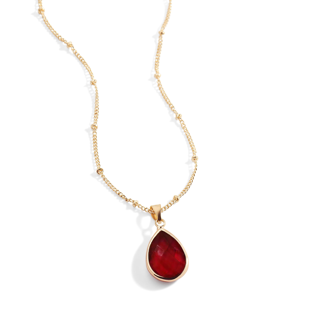 Gold necklace with a red teardrop pendant on a white background