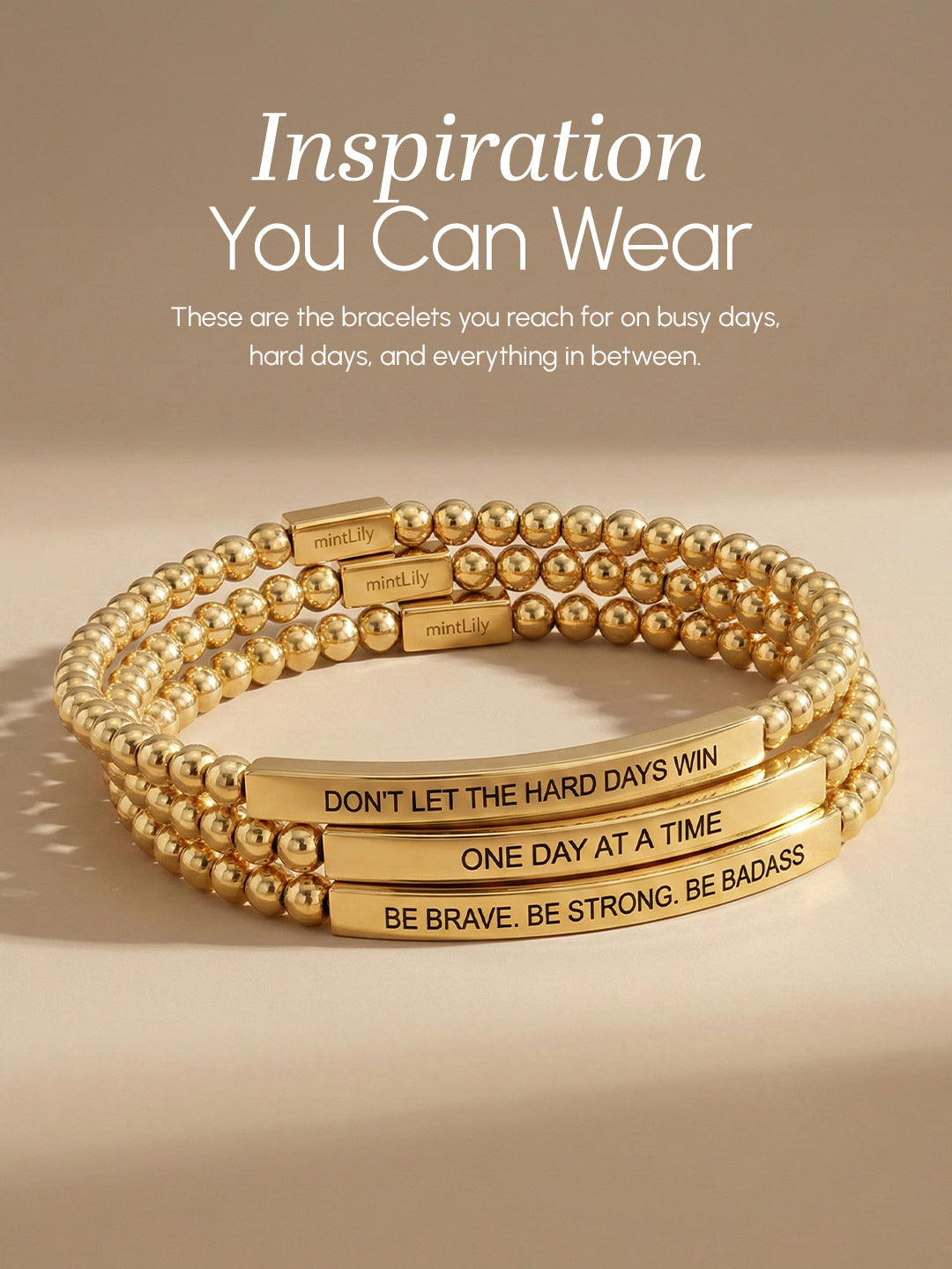 Gold bracelets with motivational phrases on a beige background