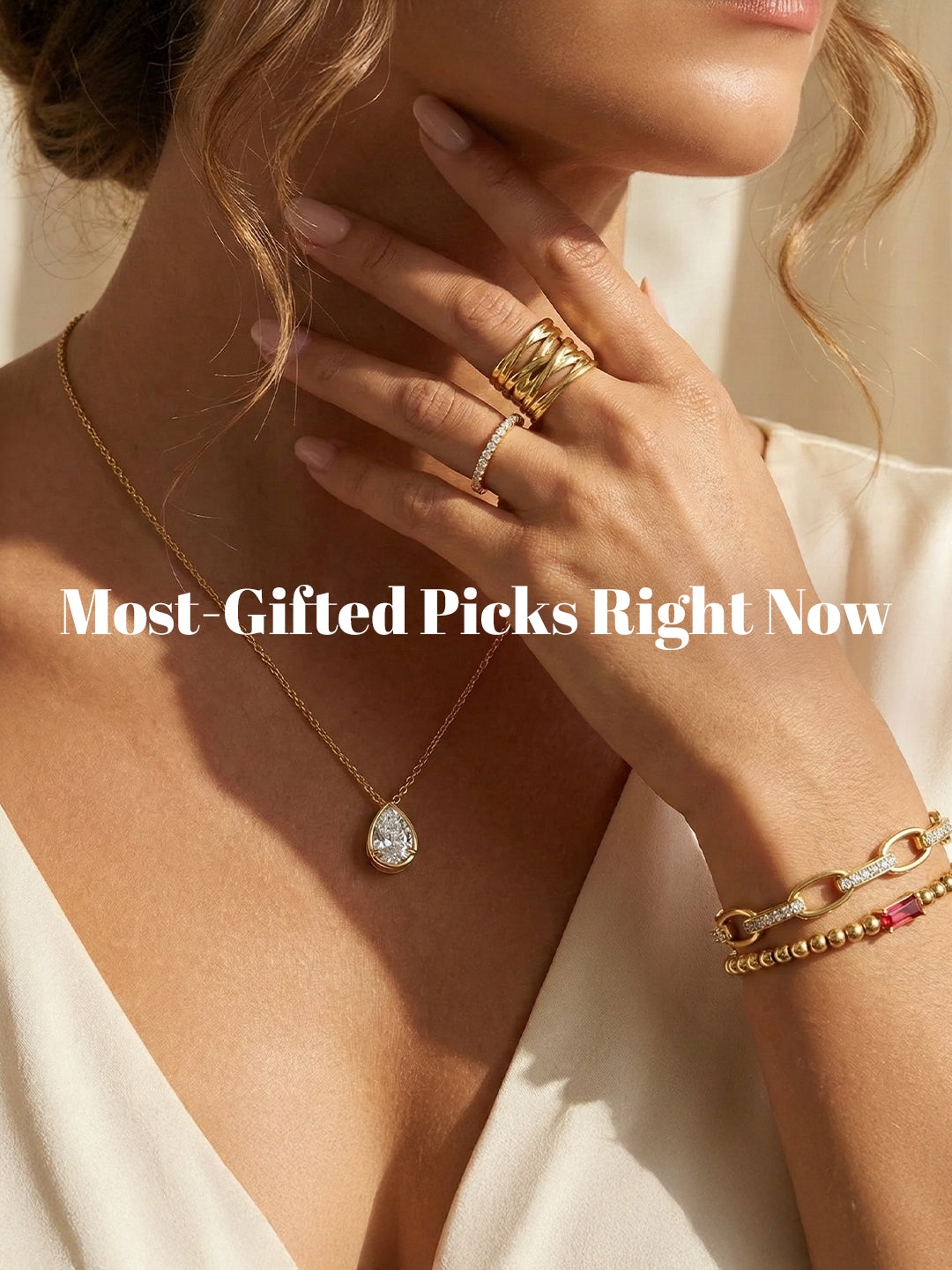 Close-up of a person wearing gold jewelry including a necklace, ring, and bracelet on a neutral background.
