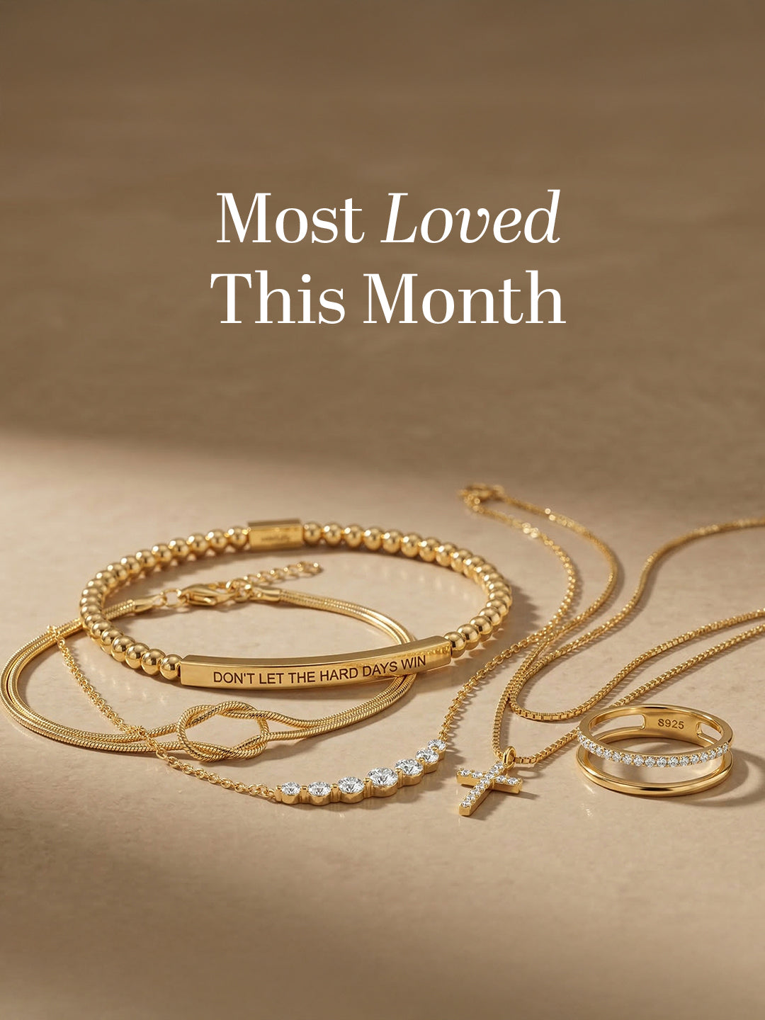 Flat lay of gold jewelry including beaded bracelet, cross necklace, rings, and layered chains with ‘Most Loved This Month’ text.