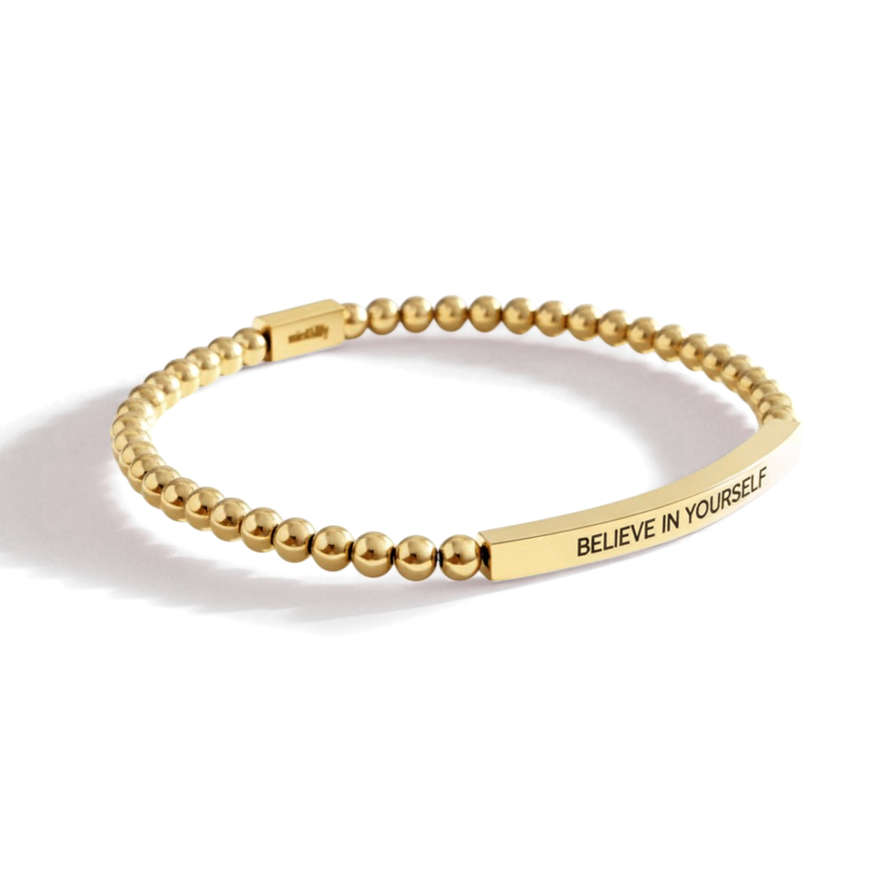 Gold beaded bracelet with 'BELIEVE IN YOURSELF' engraving on a light background