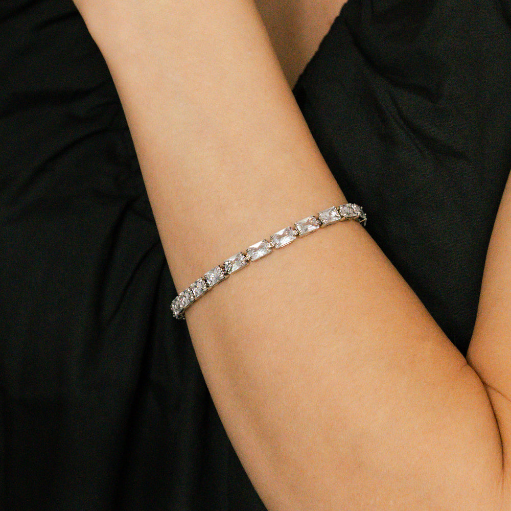 Silver bracelet with clear stones on a person's wrist against a black background