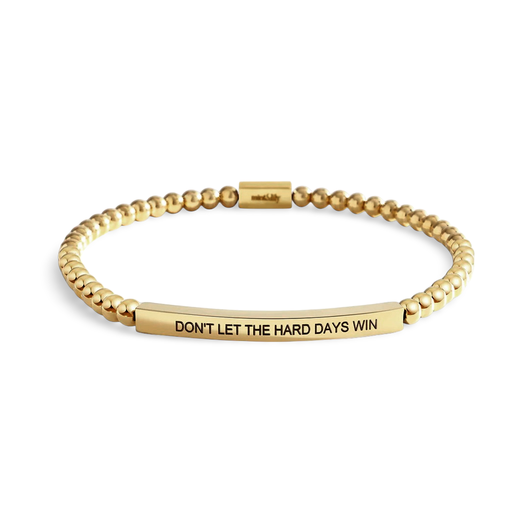 Gold beaded bracelet with motivational message on a light background