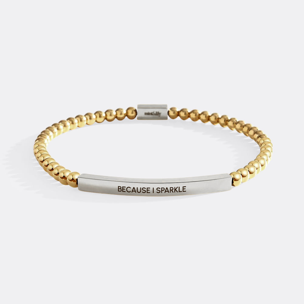 Gold beaded bracelet with a silver bar featuring 'BECAUSE I SPARKLE' on a white background