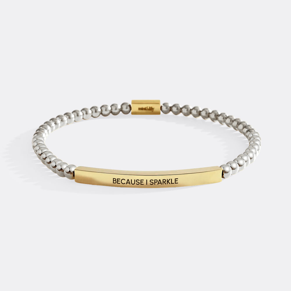 Bracelet with gold and silver beads and 'BECAUSE I SPARKLE' engraving on a white background