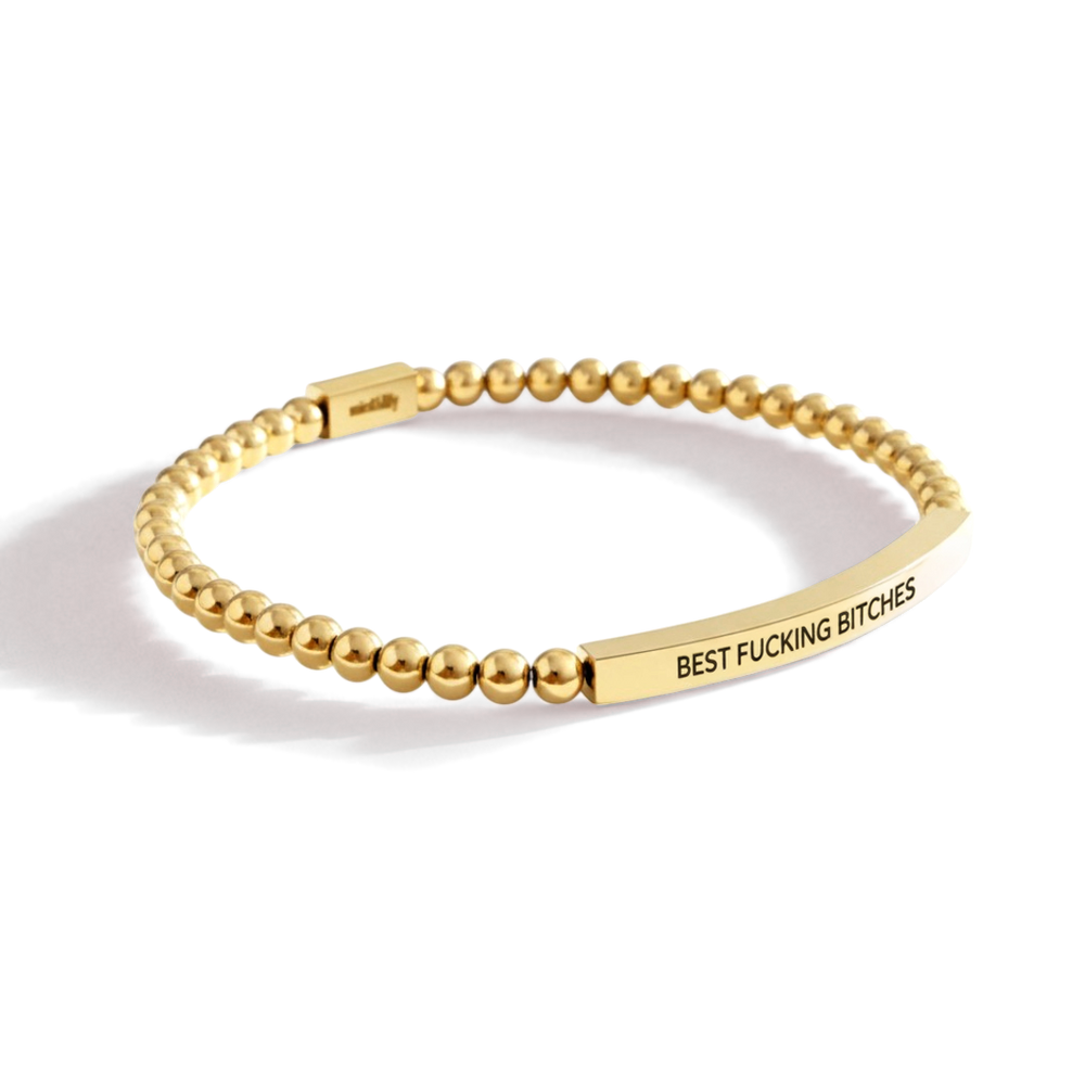 Gold beaded bracelet with a bar featuring text on a white background