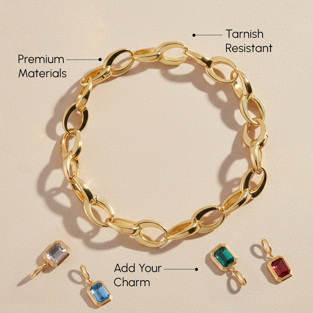 Gold chain bracelet with attached charms on a beige background