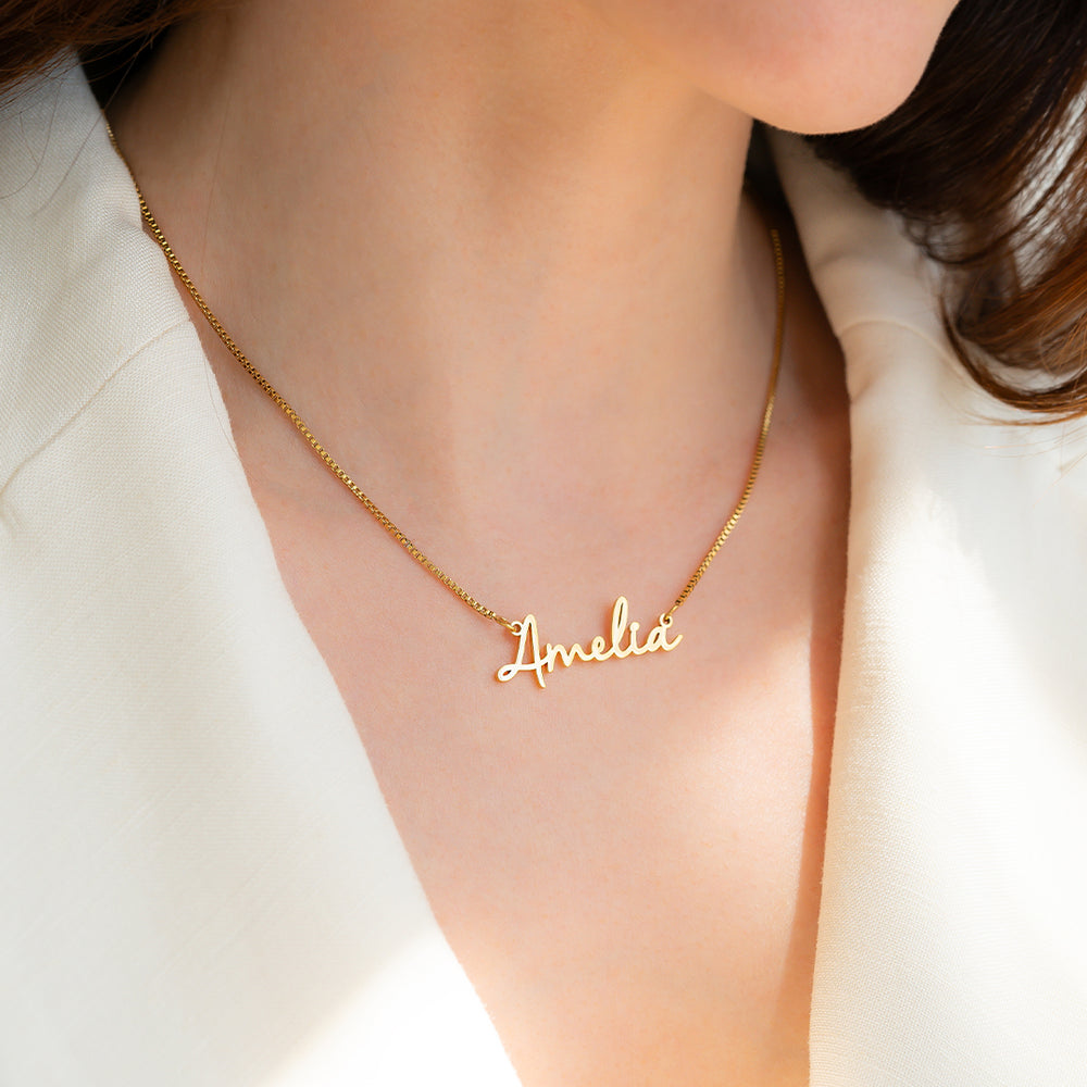 Gold necklace with 'Amelia' pendant on a person wearing a white shirt