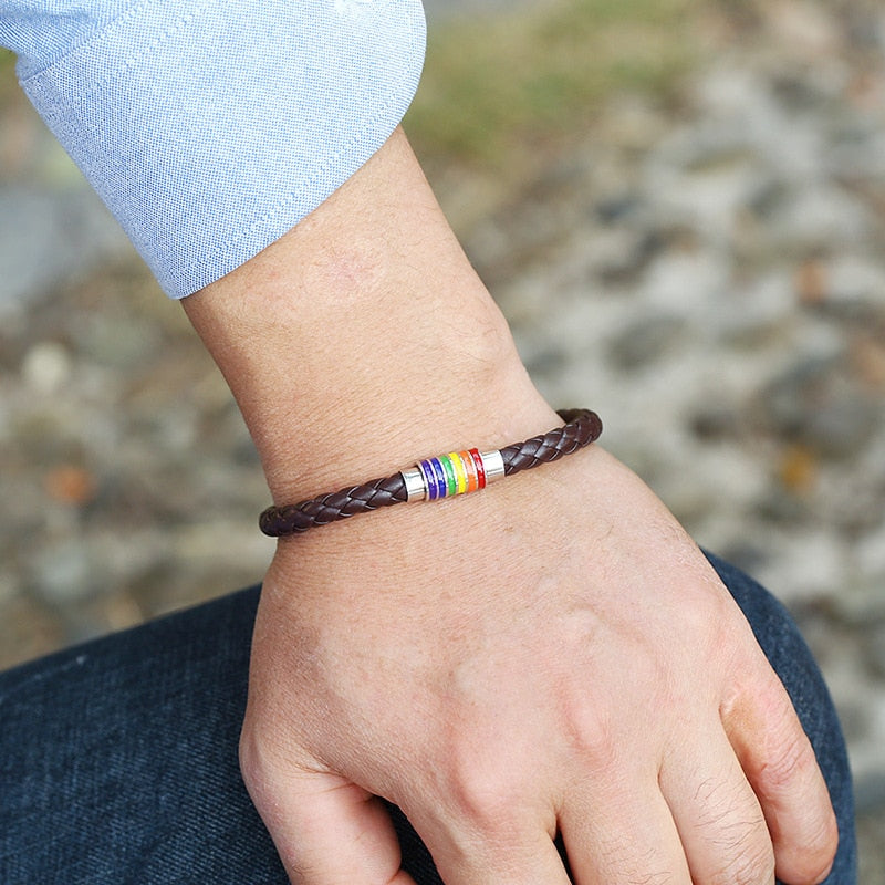 A person's wrist wearing a braided leather rainbow bracelet with a magnetic clasp.