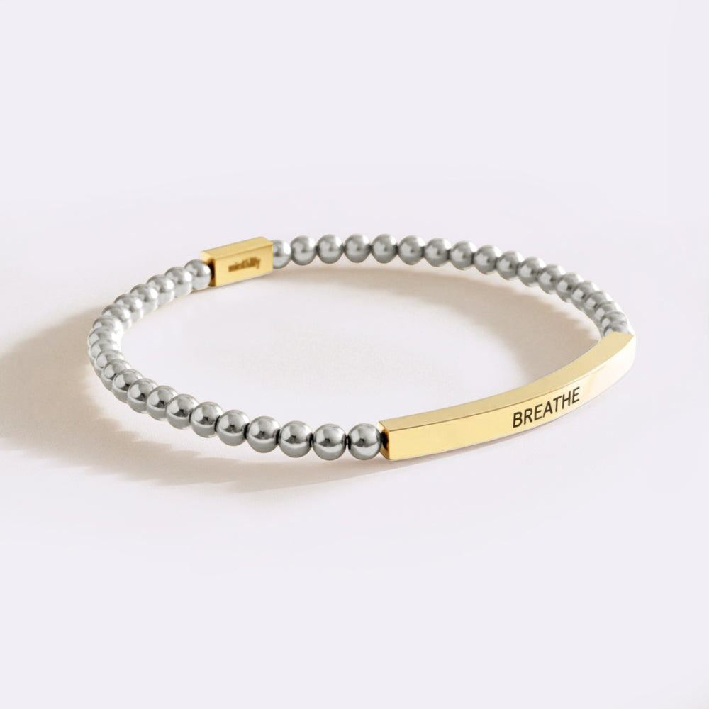 Bracelet with gold bar and gray beads on a white background