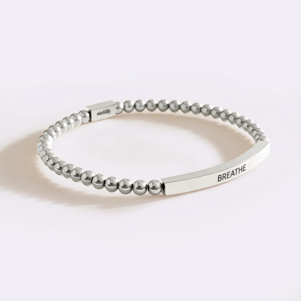 Silver beaded bracelet with 'BREATHE' engraving on a white background
