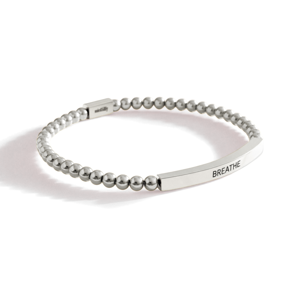 Silver beaded bracelet with 'BREATHE' engraving on a white background