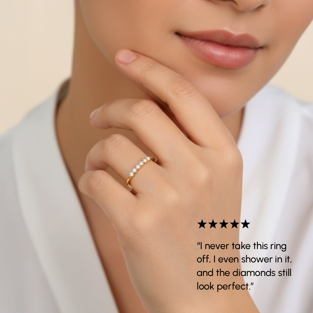 Close-up of a hand wearing a gold ring with pearls, set against a neutral background.