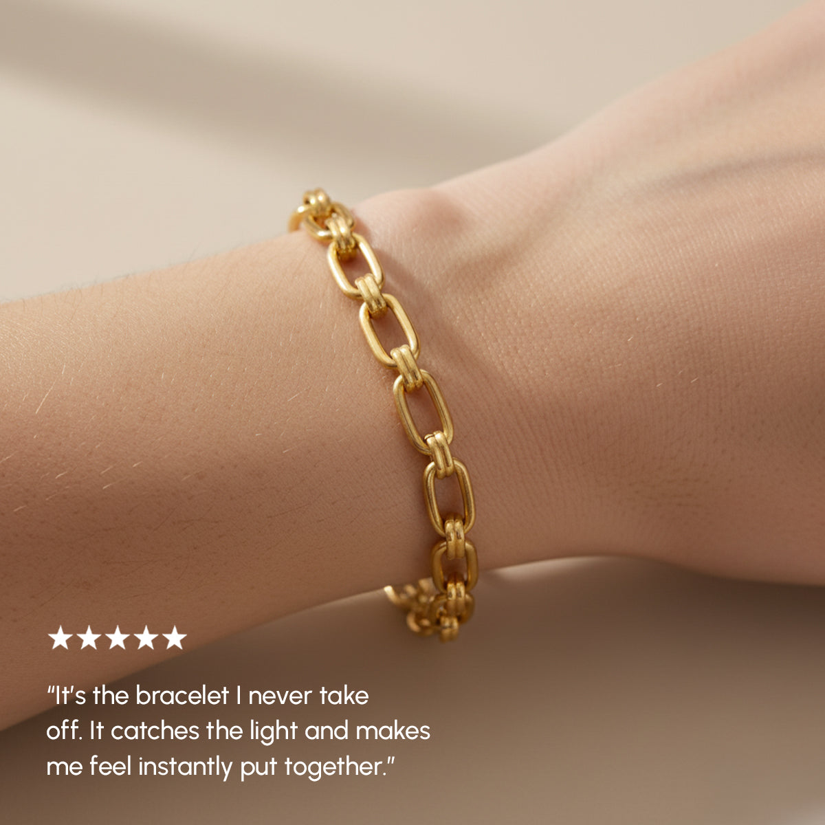 Gold chain bracelet on a wrist with a neutral background