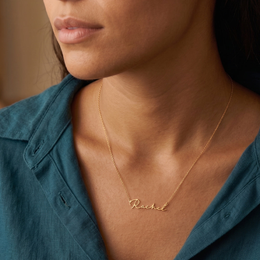 Woman wearing a gold necklace with 'Rachel' engraved on it, against a neutral background.