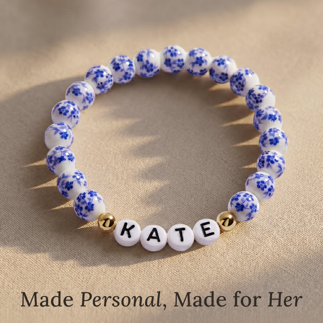 Bracelet with blue floral beads and letter beads spelling 'KATE' on a beige background.