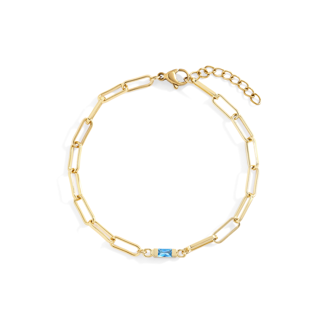 Gold chain bracelet with a blue gemstone on a white background