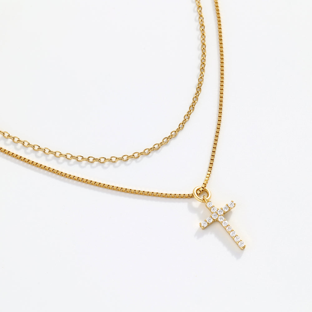 Gold necklace with a small cross pendant on a white background