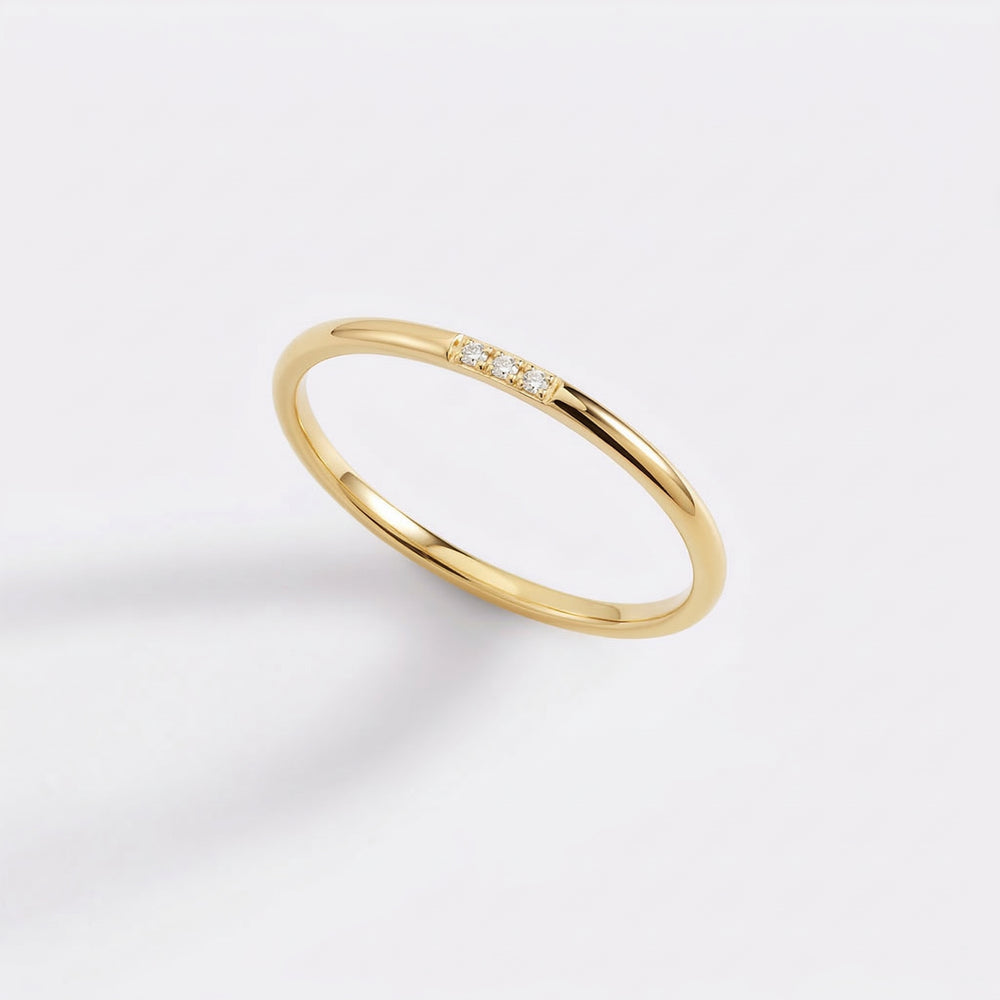 Gold ring with small diamonds on a light gray background