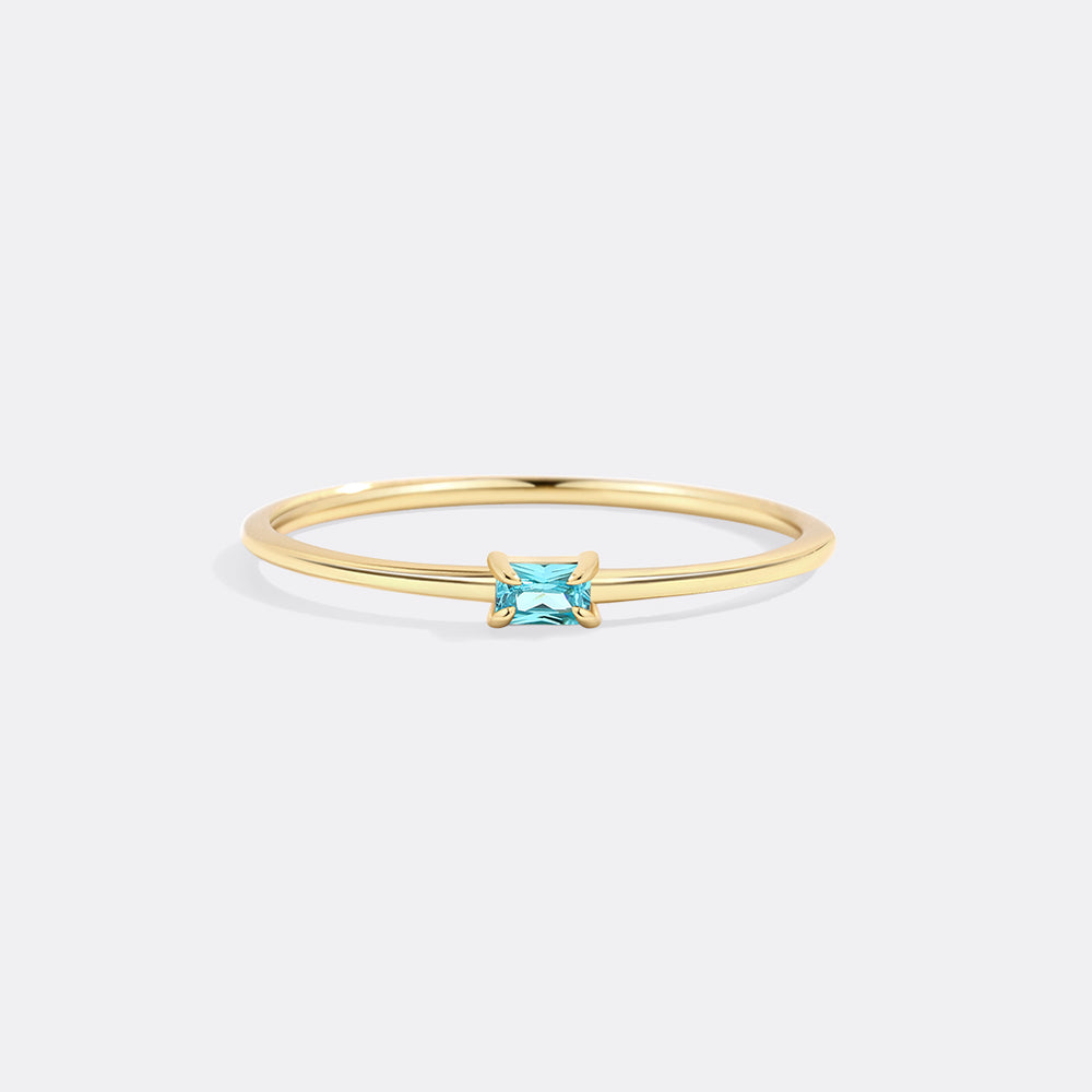 Gold ring with a blue gemstone on a white background