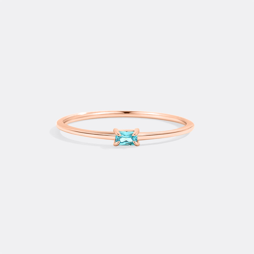 Rose gold ring with a blue gemstone on a white background