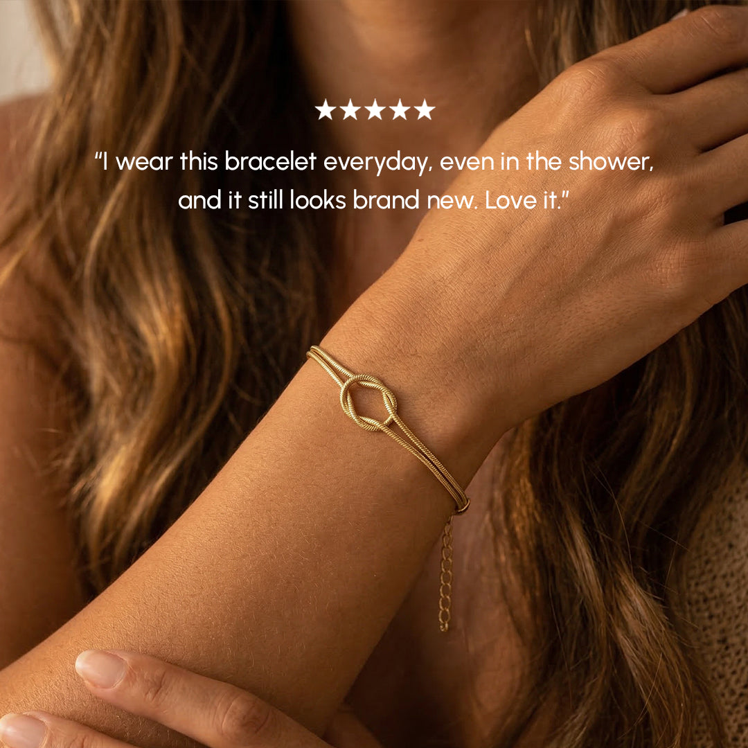 Person wearing a gold bracelet with a neutral background