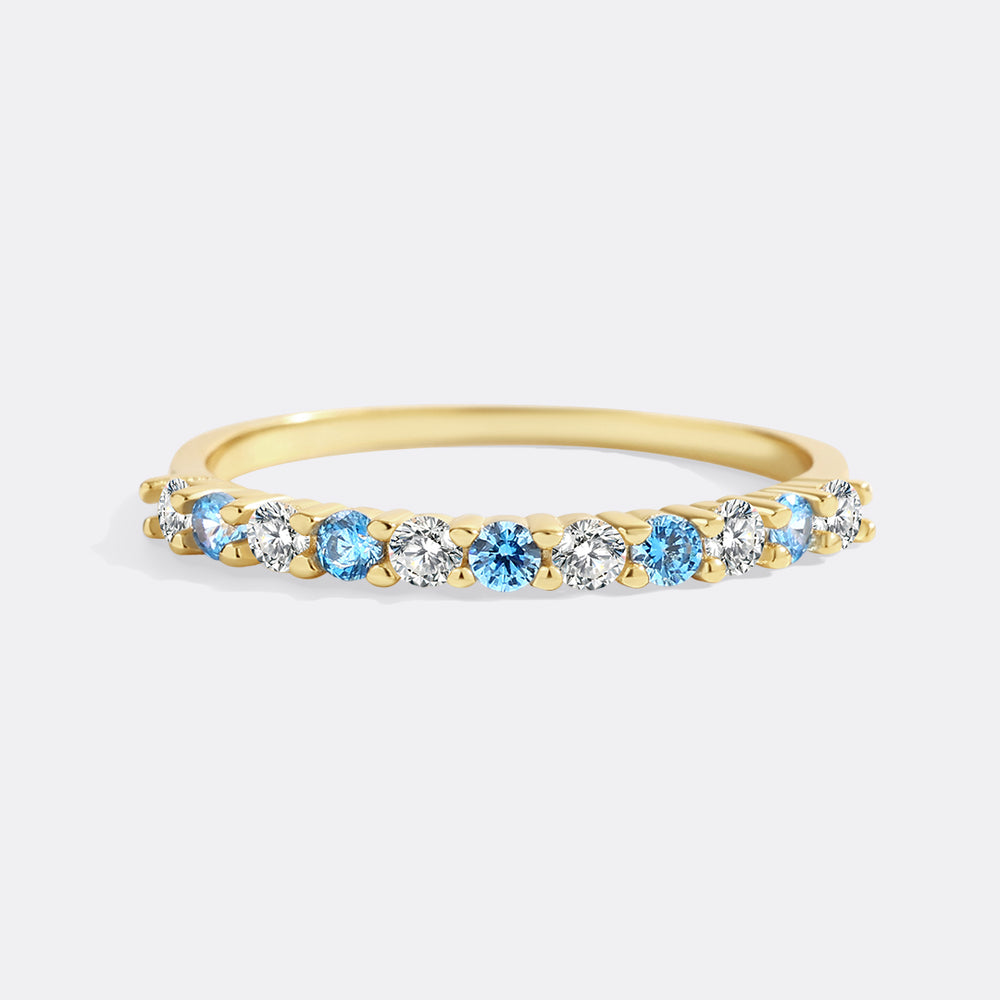 Gold ring with blue and clear gemstones on a white background