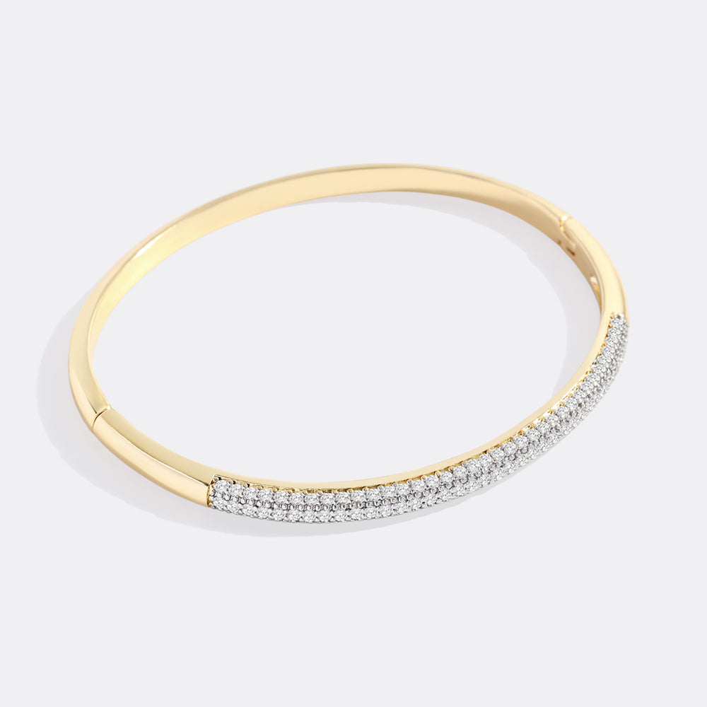 Gold bracelet with embedded diamonds on a light gray background