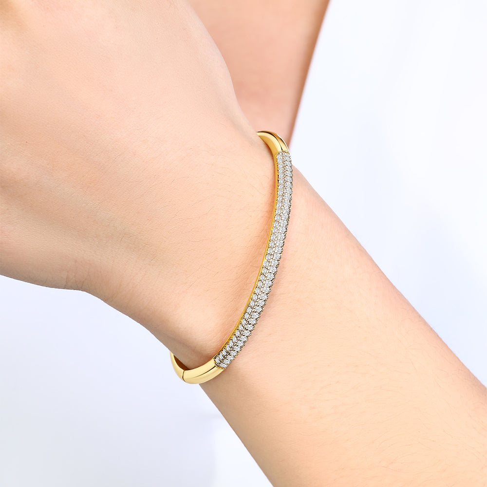 Gold bracelet with clear stones on a person's wrist against a light background