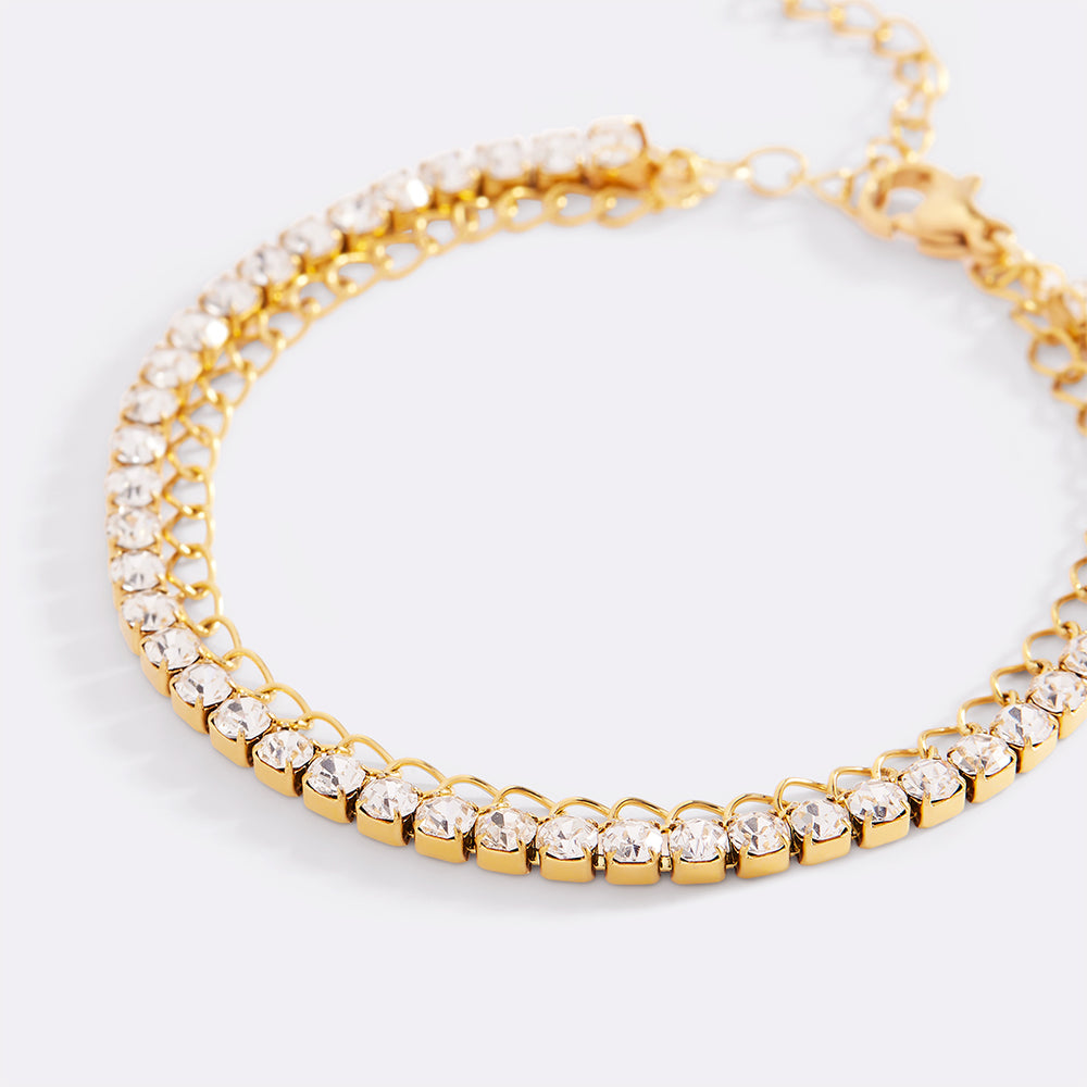 Gold bracelet with clear gemstones on a light gray background