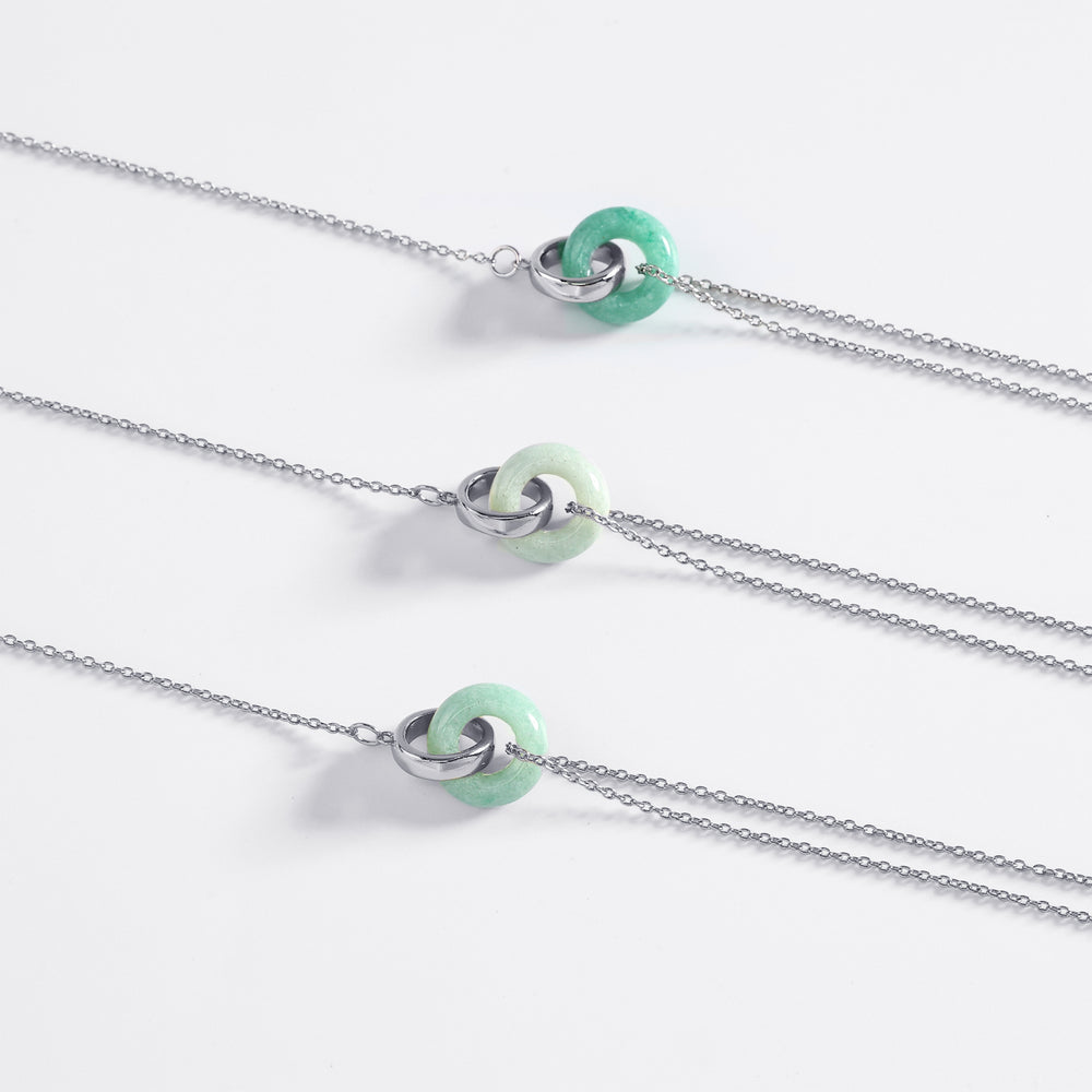 Three silver necklaces with green beads on a white background