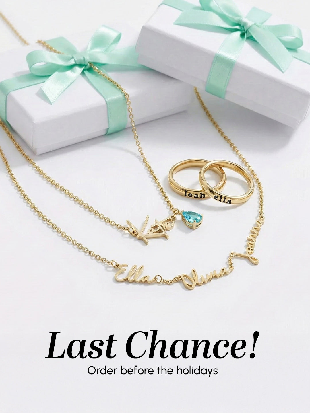 Gold necklaces with name charms on a white surface with gift boxes.