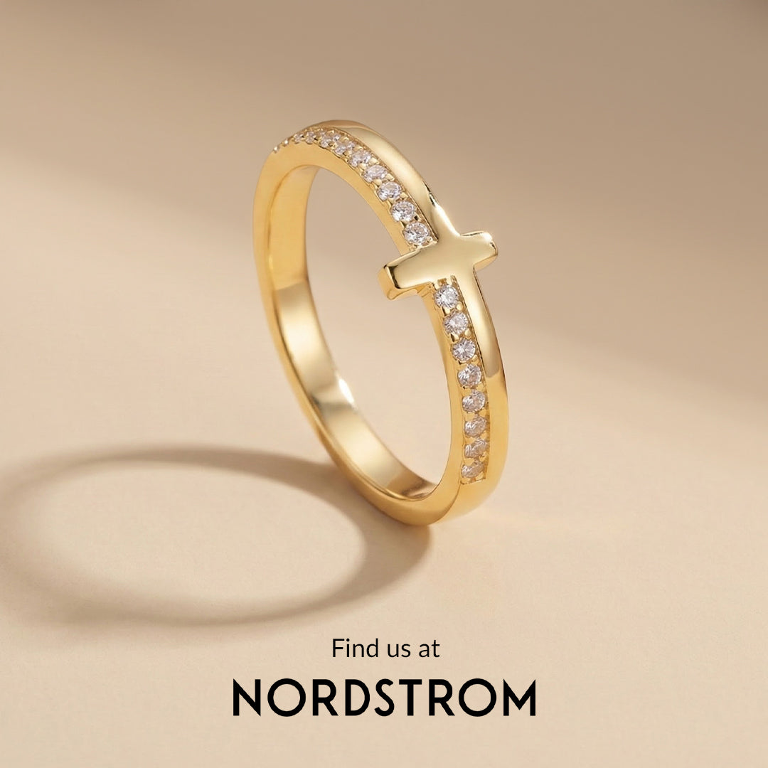 Gold ring with a cross design on a beige background, featuring the Nordstrom logo.