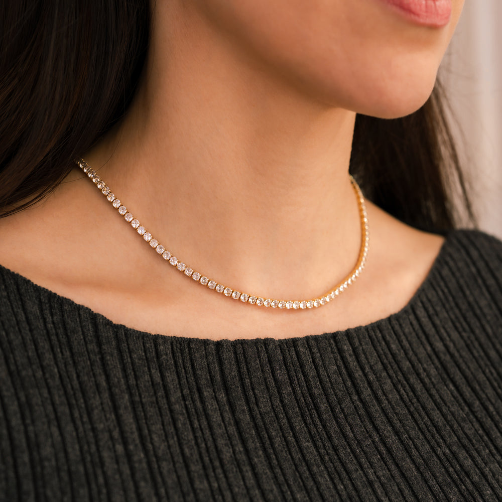Close-up of a person wearing a delicate gold necklace against a neutral background