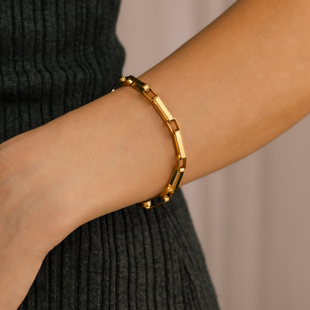Gold bracelet on a person's wrist with a neutral background