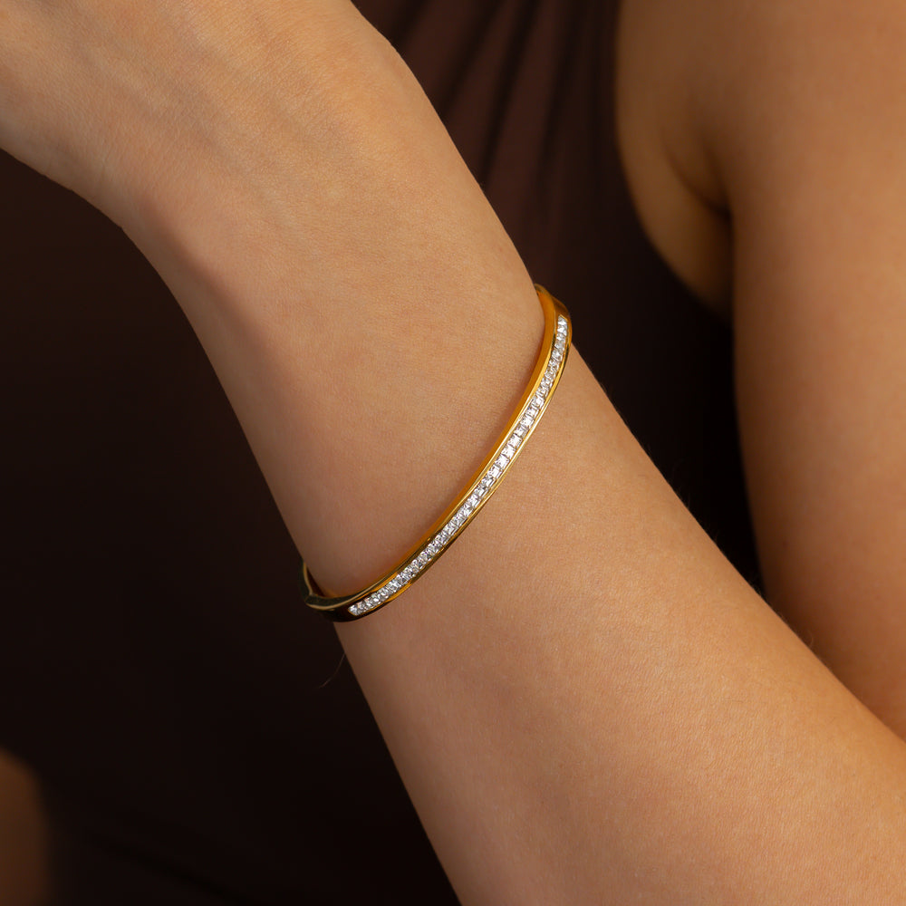 Gold bracelet with diamonds on a wrist against a dark background