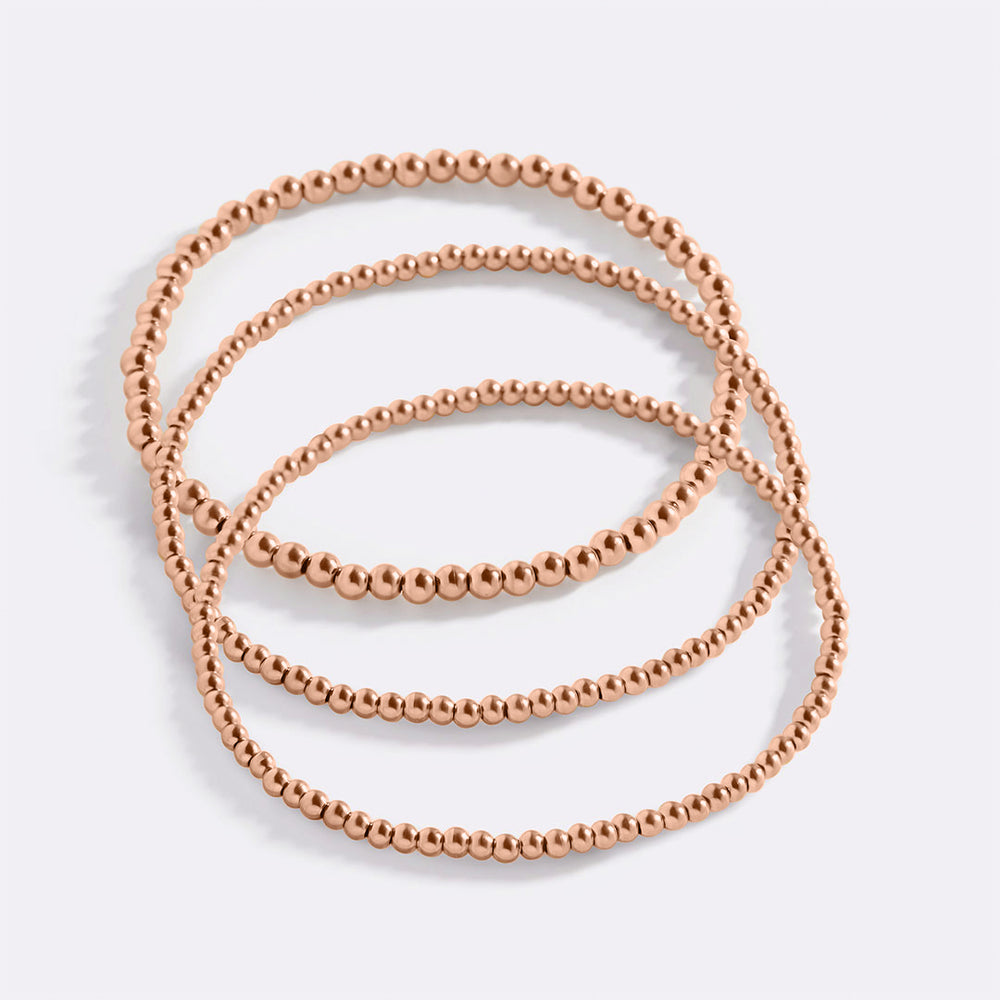 A set of gold-colored beaded bracelets stacked together.