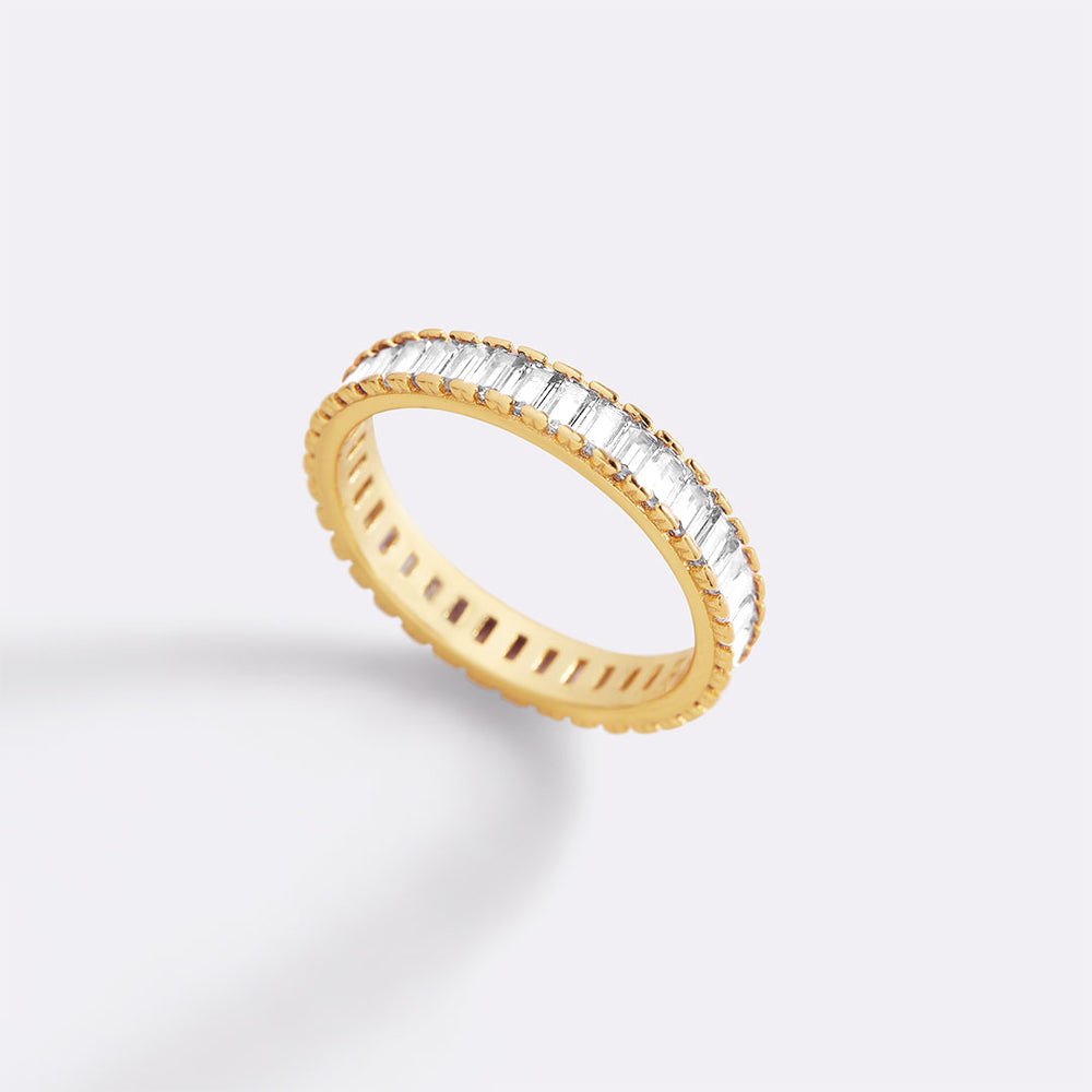 Gold ring with baguette-cut diamonds on a light gray background