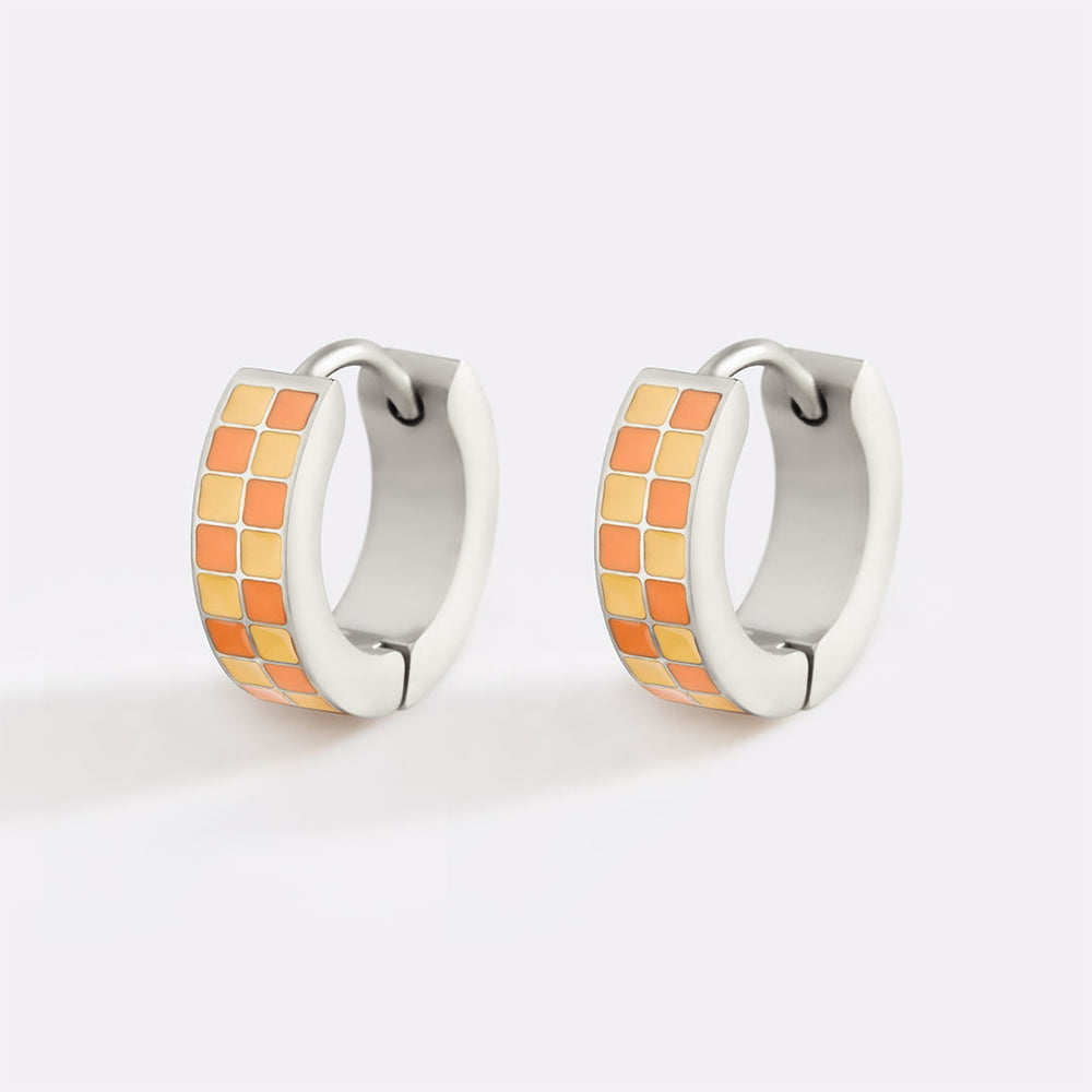 Pair of hoop earrings with orange and white checkered design on a light gray background