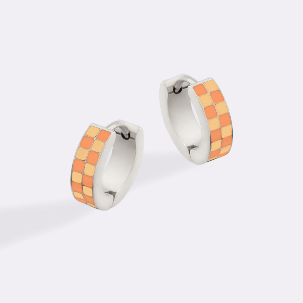 Pair of hoop earrings with orange and silver design on a white background