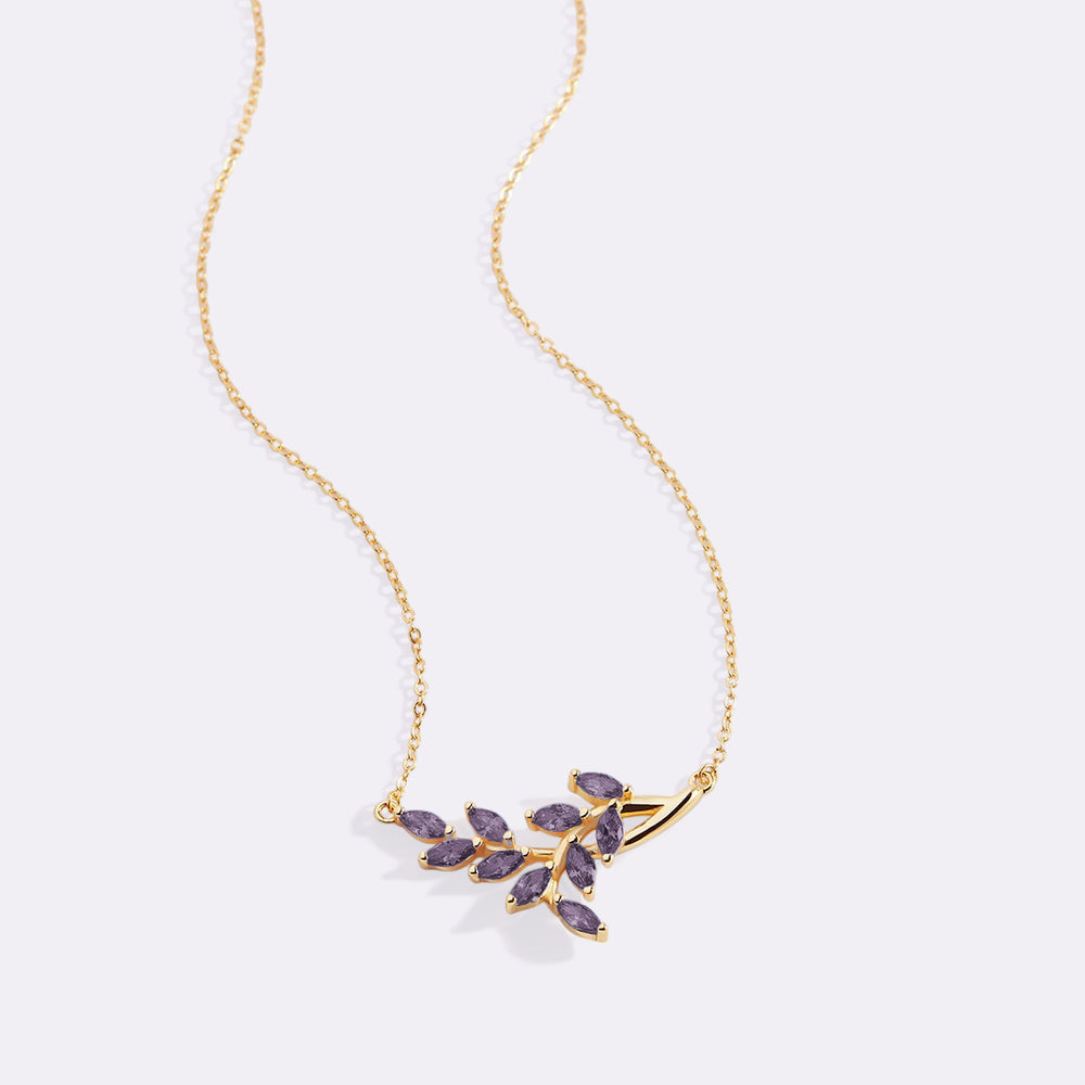 Gold necklace with purple gemstones on a light gray background