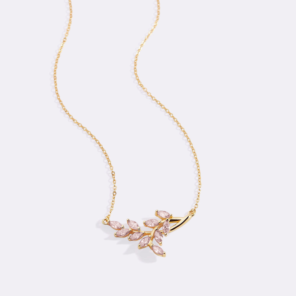 Gold necklace with pink gemstones on a light gray background