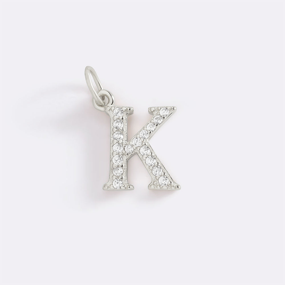 Silver letter 'K' pendant with clear stones on a white background