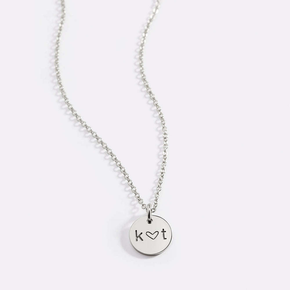 A gold-plated necklace with a circular pendant featuring the initial 'K'.