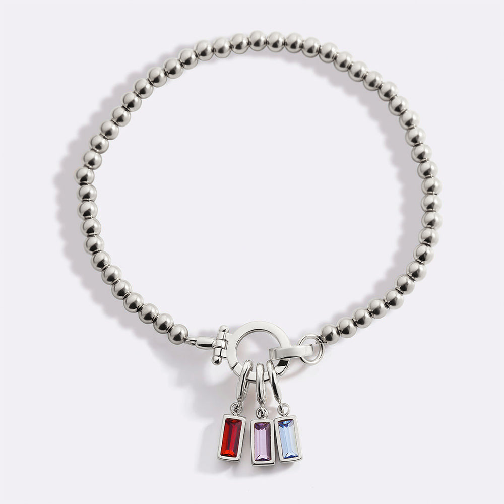 A gold-colored bracelet with bead embellishments and a charm featuring multiple birthstones in different colors.