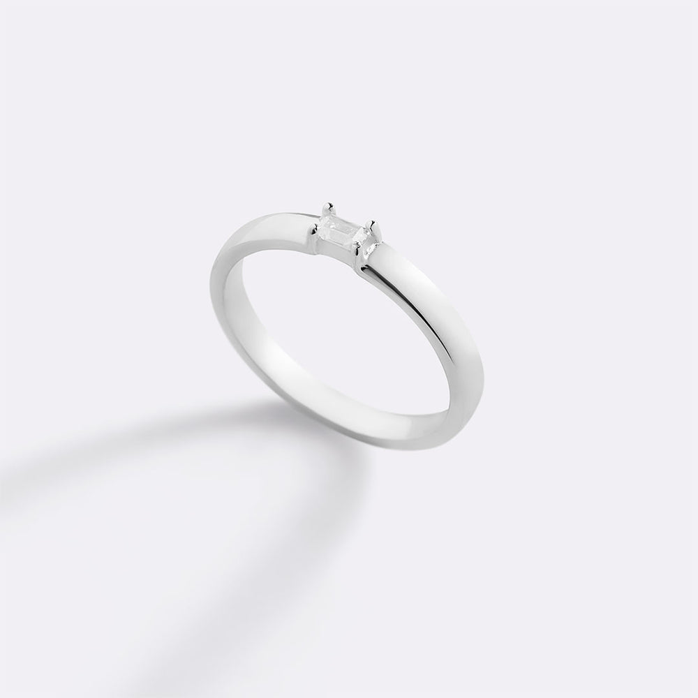 Silver ring with a small diamond on a light gray background
