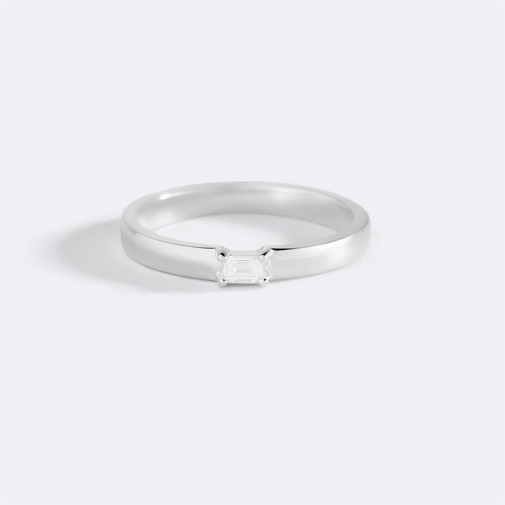 Silver ring with a small diamond on a light gray background
