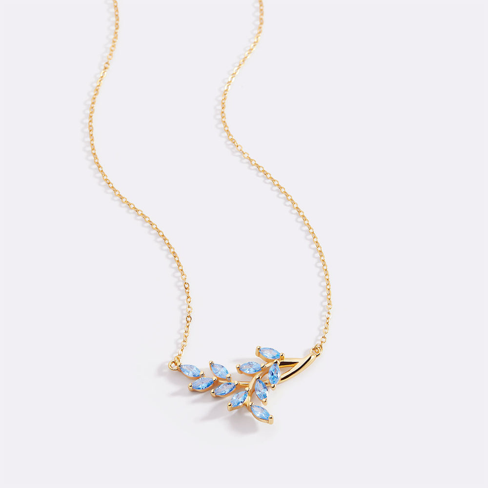 Gold necklace with blue gemstones on a light gray background
