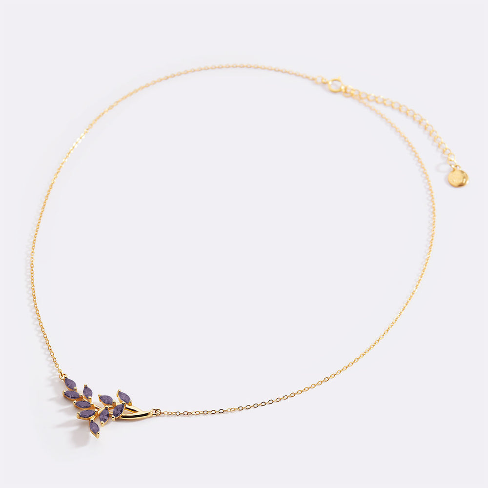 Gold necklace with purple gemstones on a light gray background