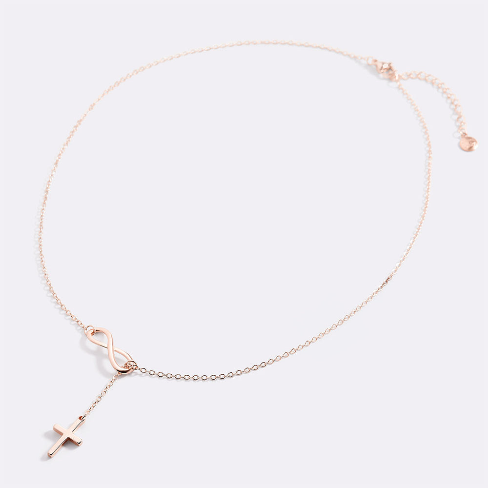 Rose gold necklace with a cross pendant on a light gray background